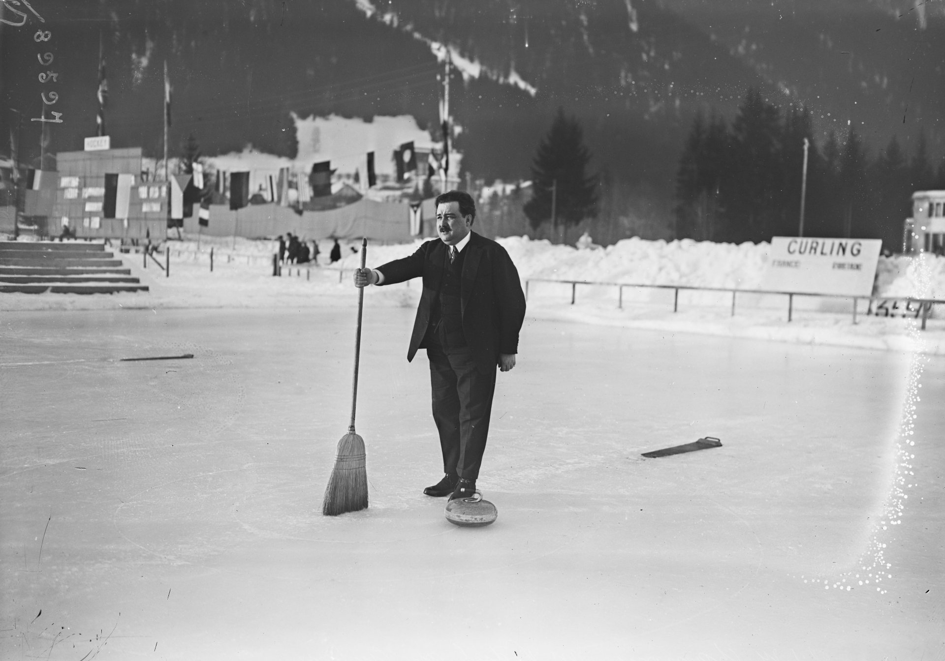 Es ist ein Mann mit einem Besen auf dem Eis zu sehen.