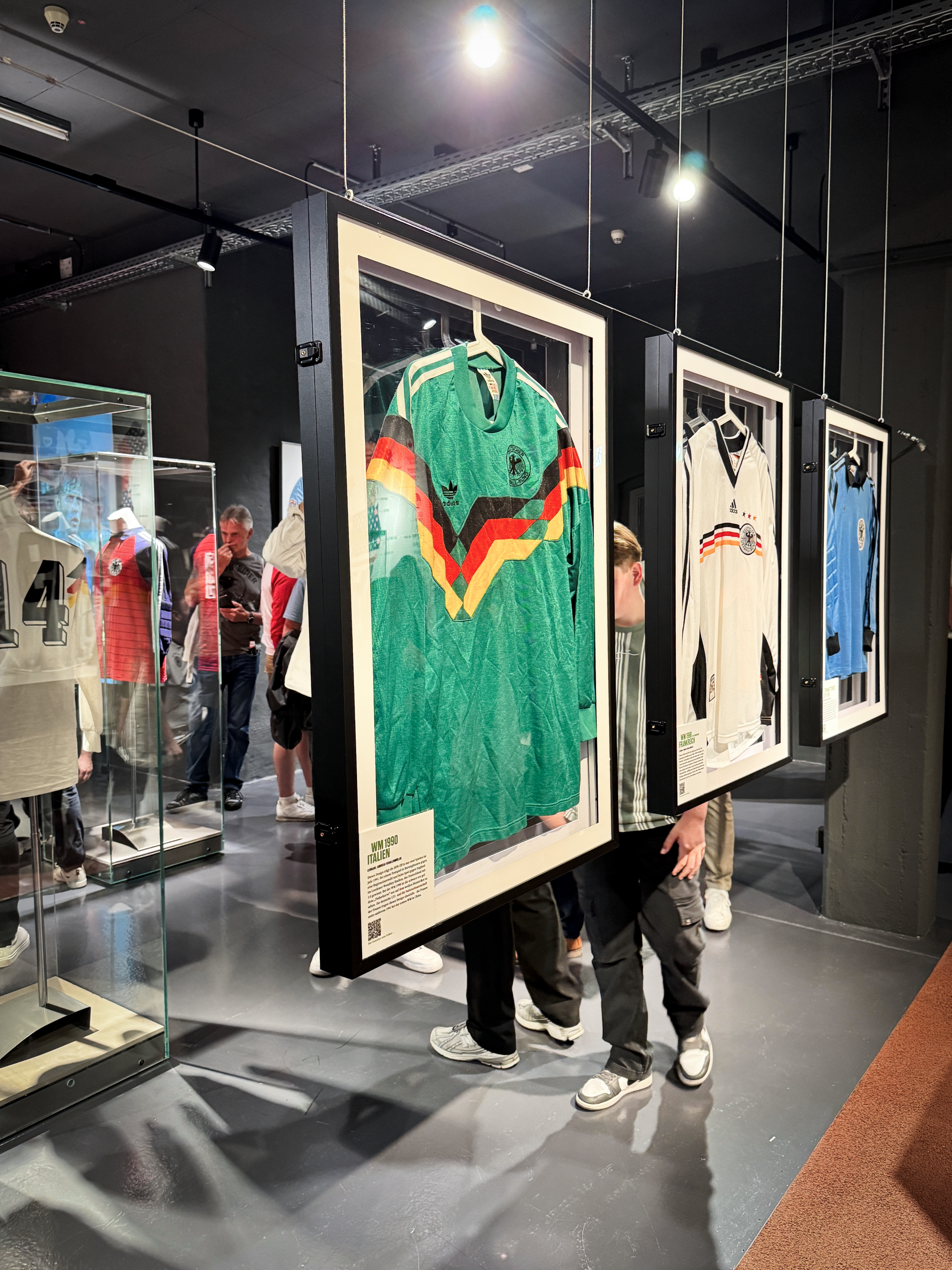 Einblick in die Trikot-Ausstellung. Drei Trikots sind in jeweils einem Rahmen ausgehängt.
