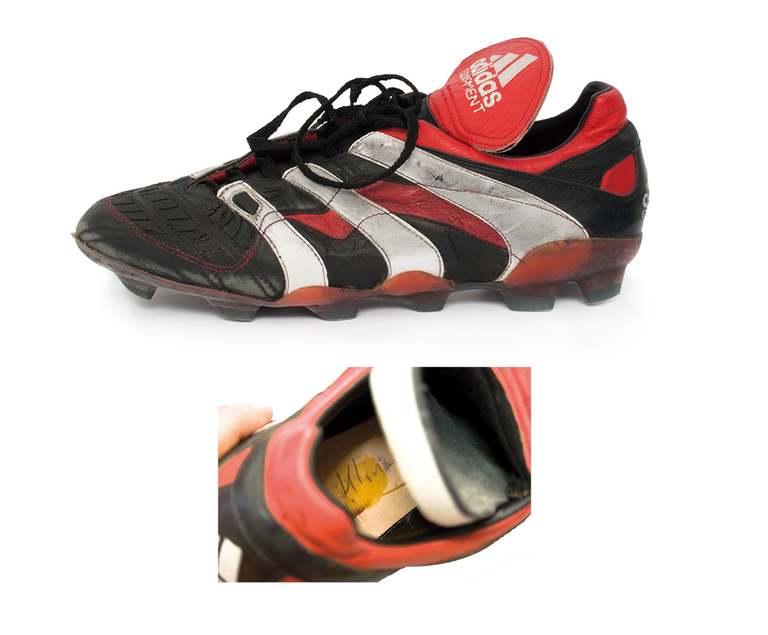 Fußballschuh der Marke Adidas in Schwarz und Rot mit weißen Streifen