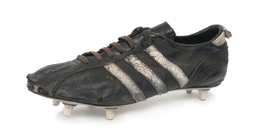 Schwarzer Fußballschuh der Marke Adidas mit starken Gebrauchsspuren